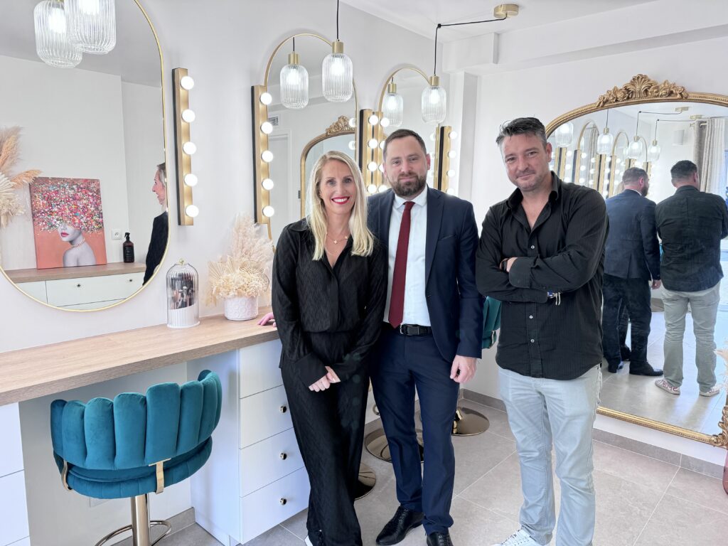 Jennifer Perseverante, accompagnée de Jonathan Wofsy, le Maire de Chevry-Cossigny, et d'Alexandre Chevalier, adjoint en charge de la vie économique, dans son élégant studio de maquillage. Le trio est entouré d'un décor sophistiqué, avec des miroirs illuminés et des tabourets en velours vert